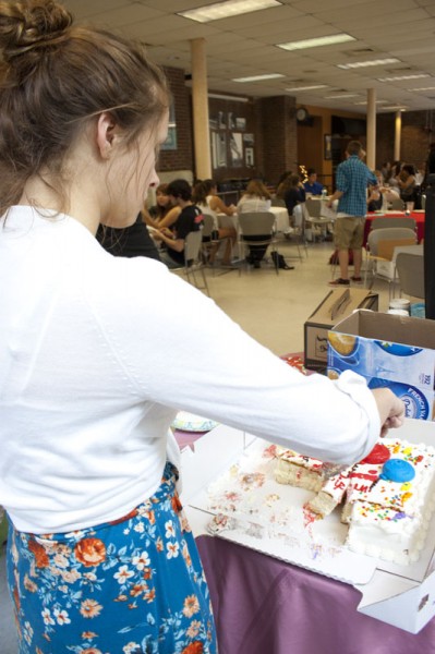 Sadie Birchfield (12) slices a piece of cake behind the food counter. | Photo by Meg Shanks