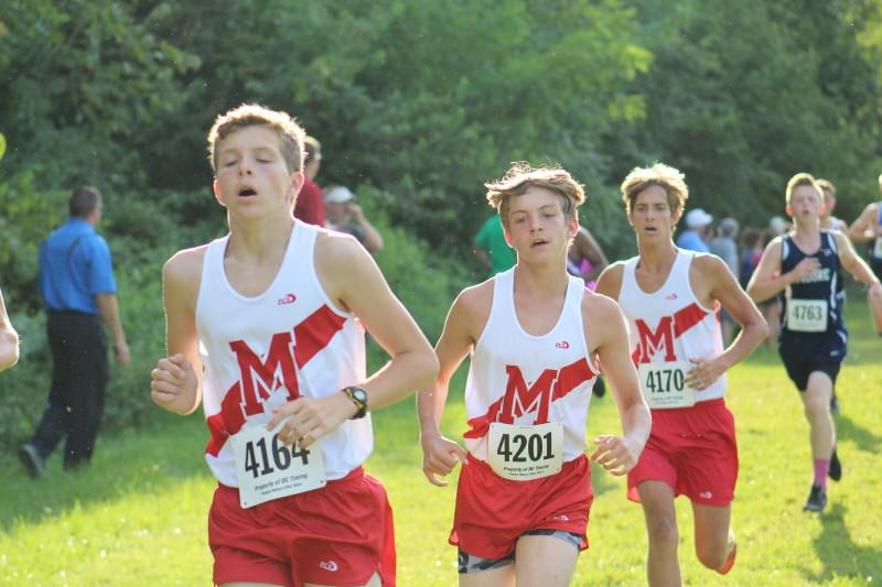 Jackson Haile (11), Clayton Wagoner (10) and Graham Jolly (11) run down the last hill of the course to finish about half of their first mile. "[When you are coming out of the woods down the first hill], the feeling is exhilarating. You feel like you can run for days," Haile said. Photo by Kate Hatter 