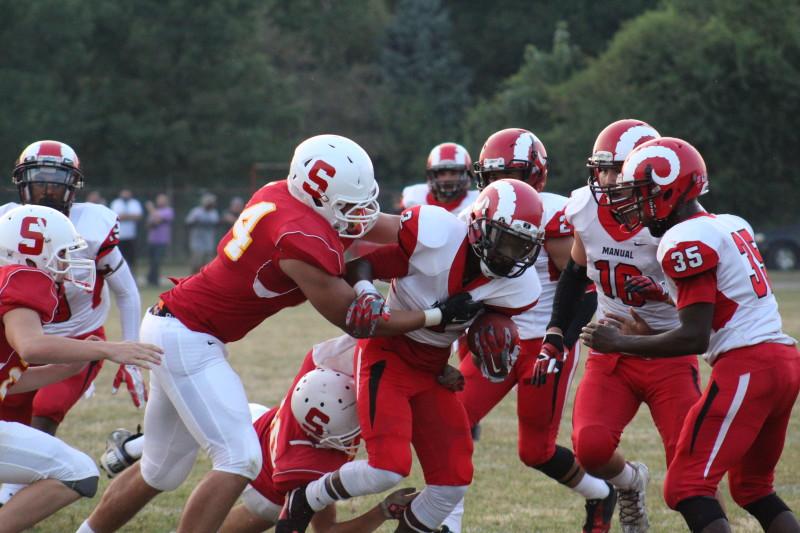Omari Alexander (12, #2) fights Seneca defenders for a large gain for Manual offense. Photo by Kate Hatter