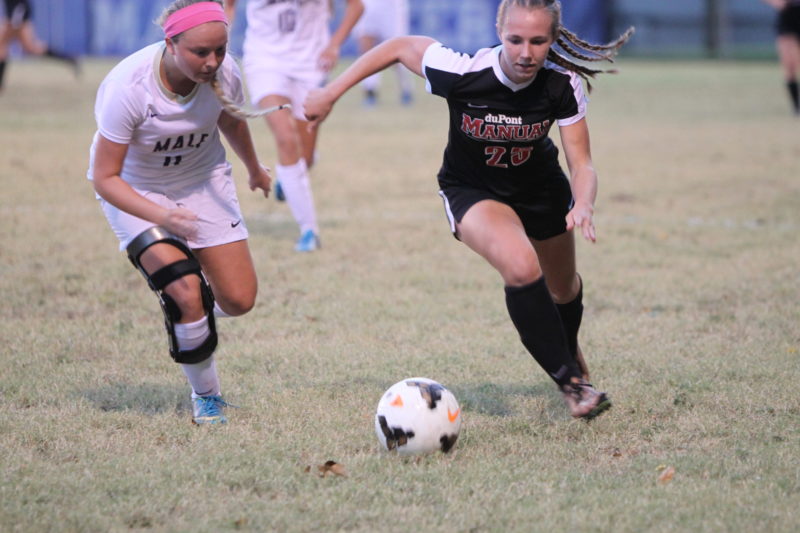 Junior Izzie Zamborini running the ball down the field with a Male player defender her. 