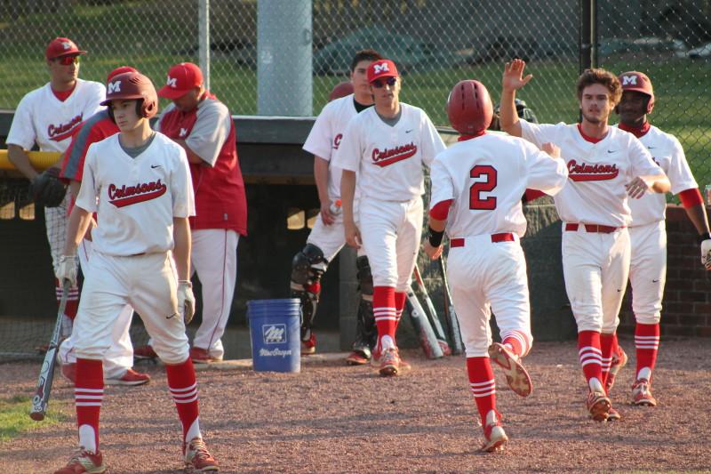Matt Olson (11, #2) celebrates with Matthew Marino (12, #7) and others after scoring Manual's first run of the game off of a hit by Aaron Sary (9, #20).